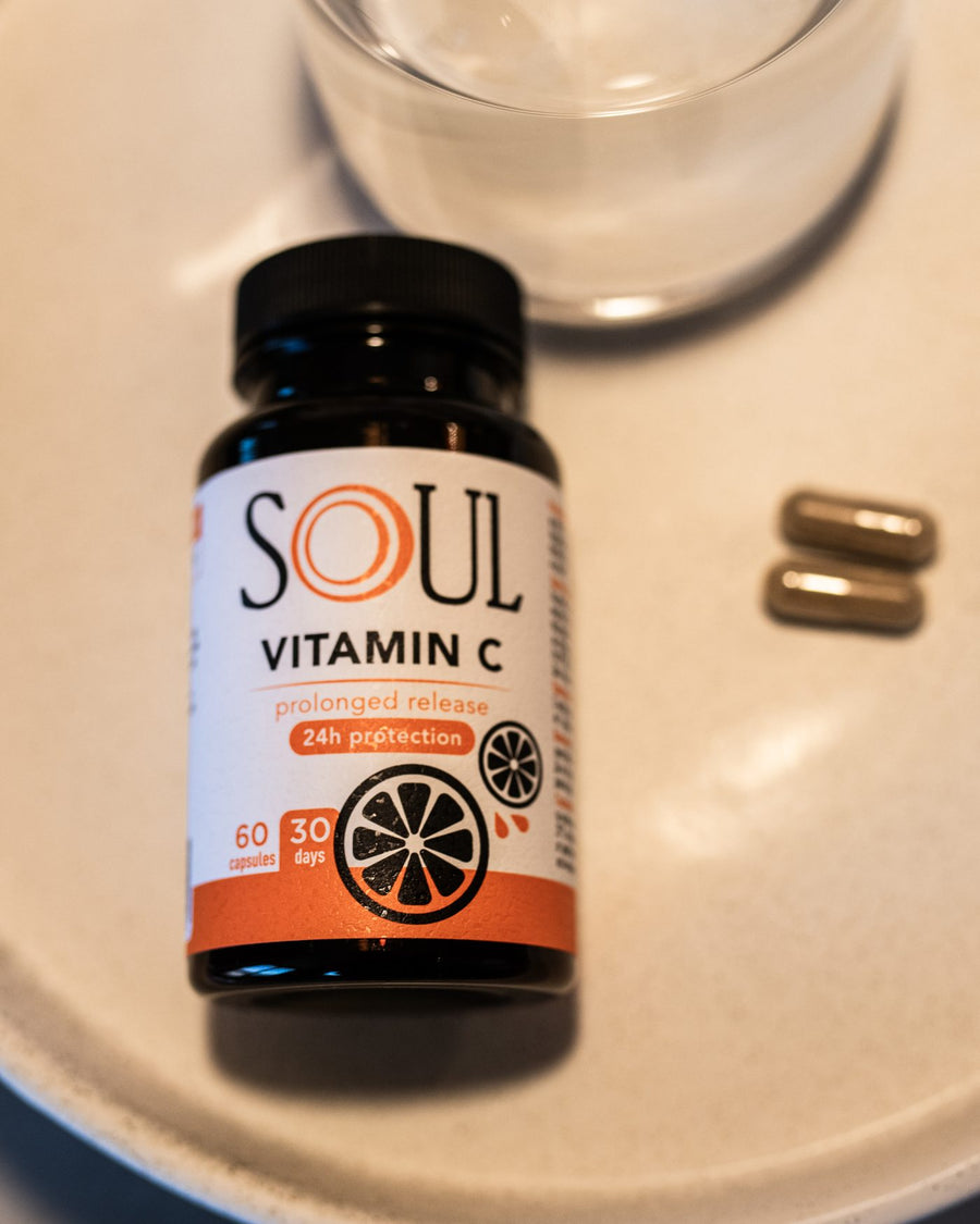 SOUL Vitamin C върху светъл поднос с две капсули до чаша вода